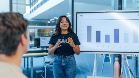 Dozentin steht vor Smartboard und erklärt